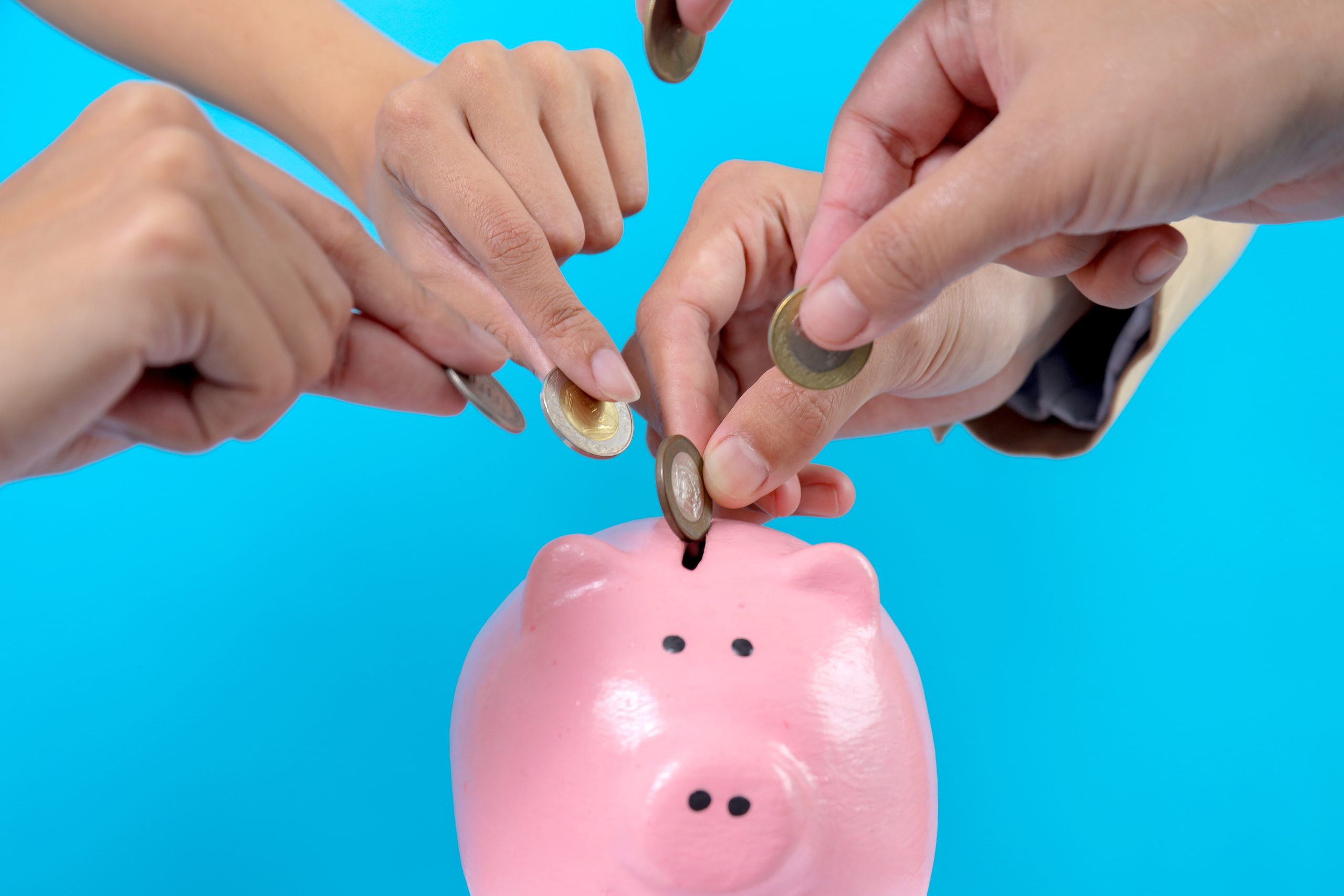 hands-putting-coins-into-piggy-bank-2025-03-16-07-53-42-utc putting money in piggy bank